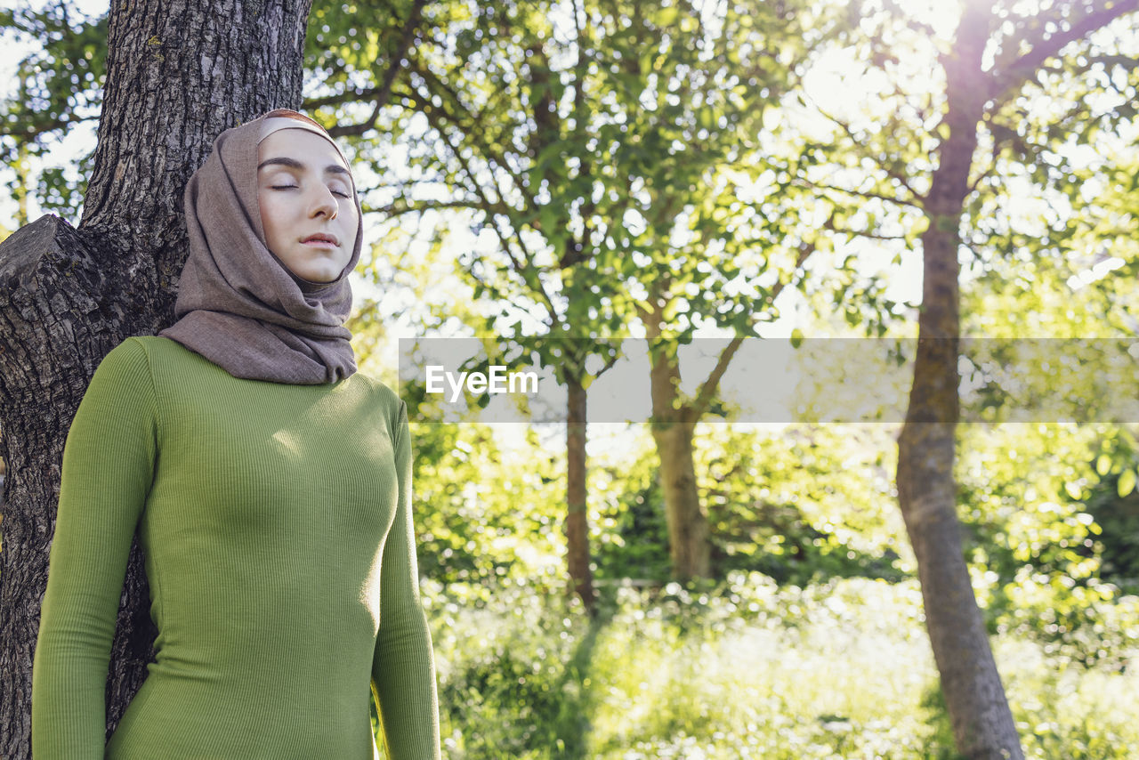 portrait of young woman standing against trees