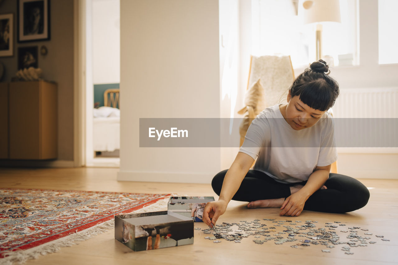 Young woman playing jigsaw puzzle at home