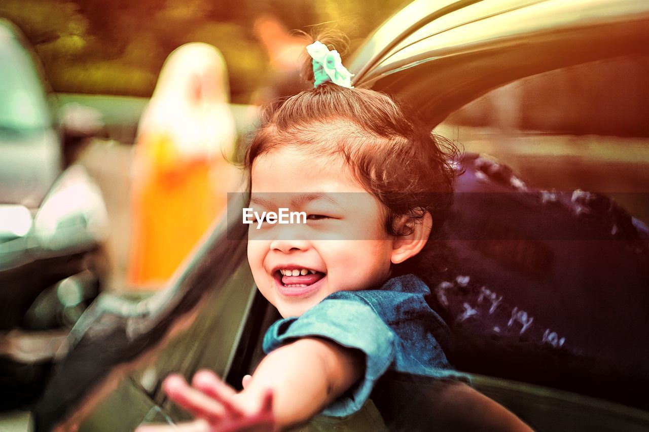 Close-up of cute girl looking through window from car