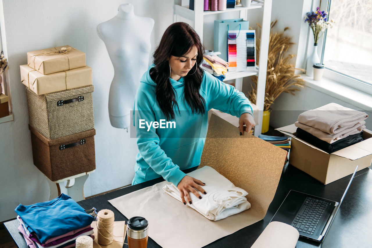 Small business owner woman packs the goods in eco packaging in office, shop.