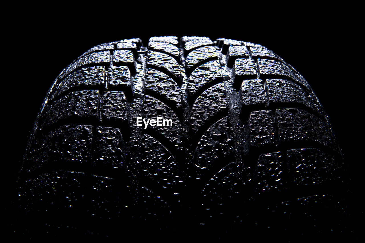 Close-up of wet tire against black background