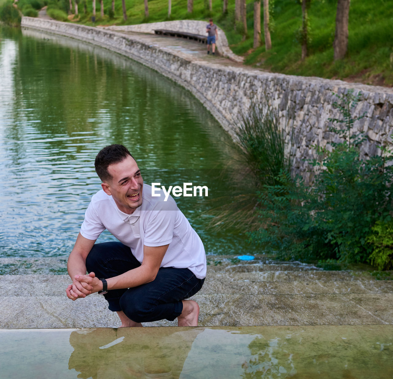 A young man in a white t-shirt inside a pond.