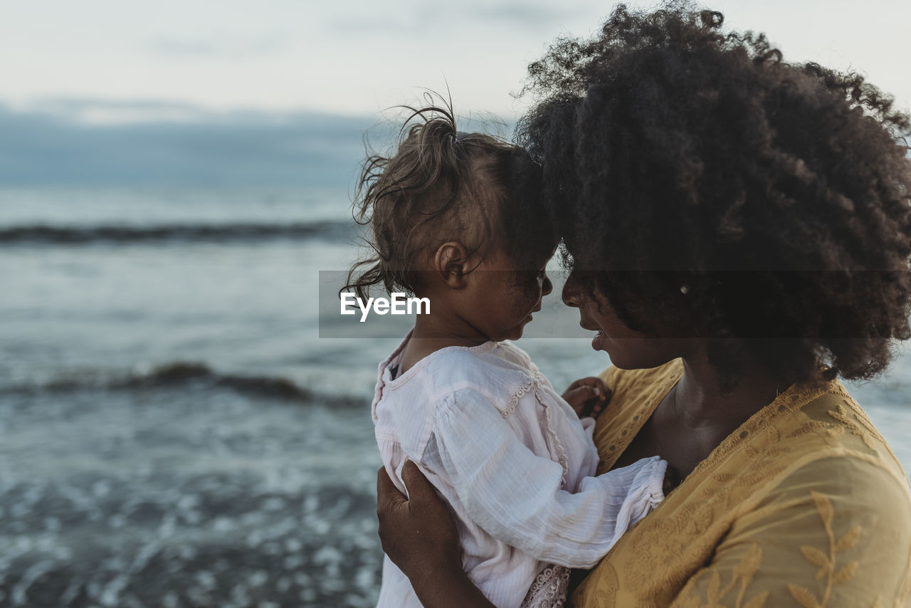 Side view of mother and daughter embracing in the ocean