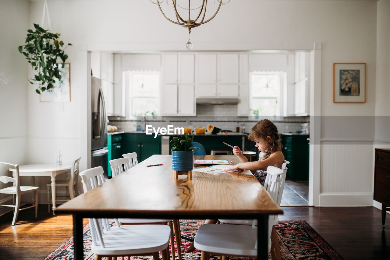 Young girl doing school work at dining room table