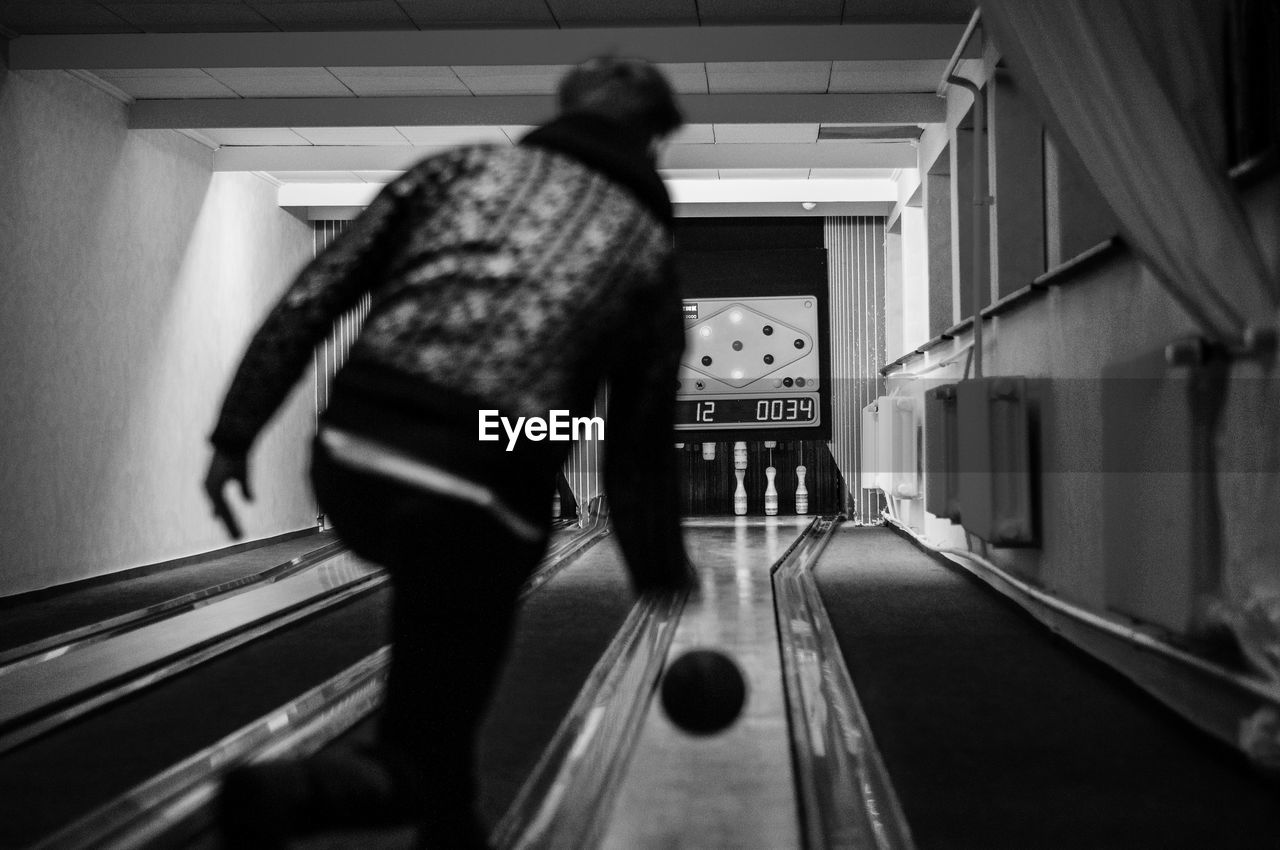 Rear view of man playing at bowling alley