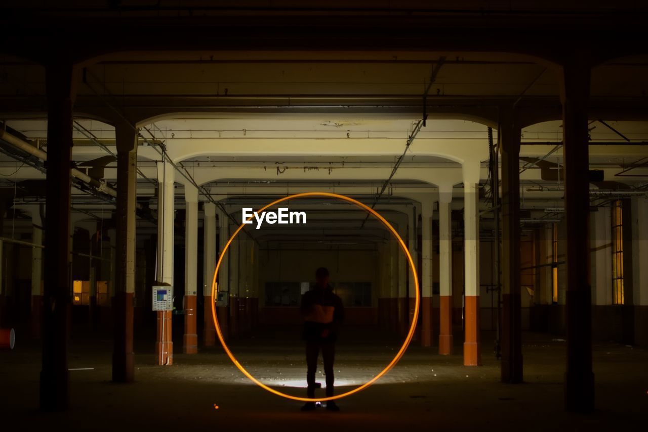 Silhouette man standing by circle shape on railroad station