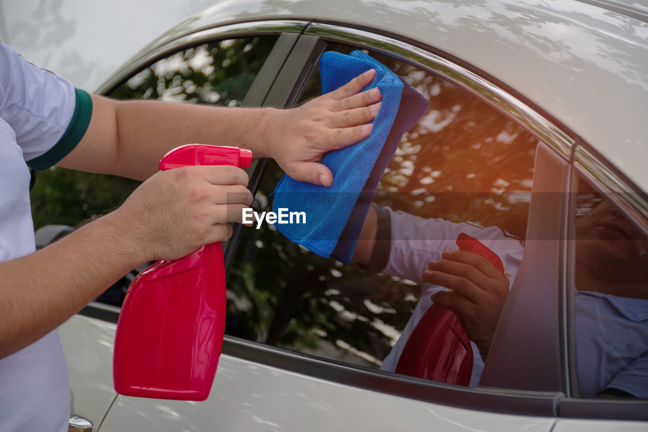 Midsection of man cleaning car window