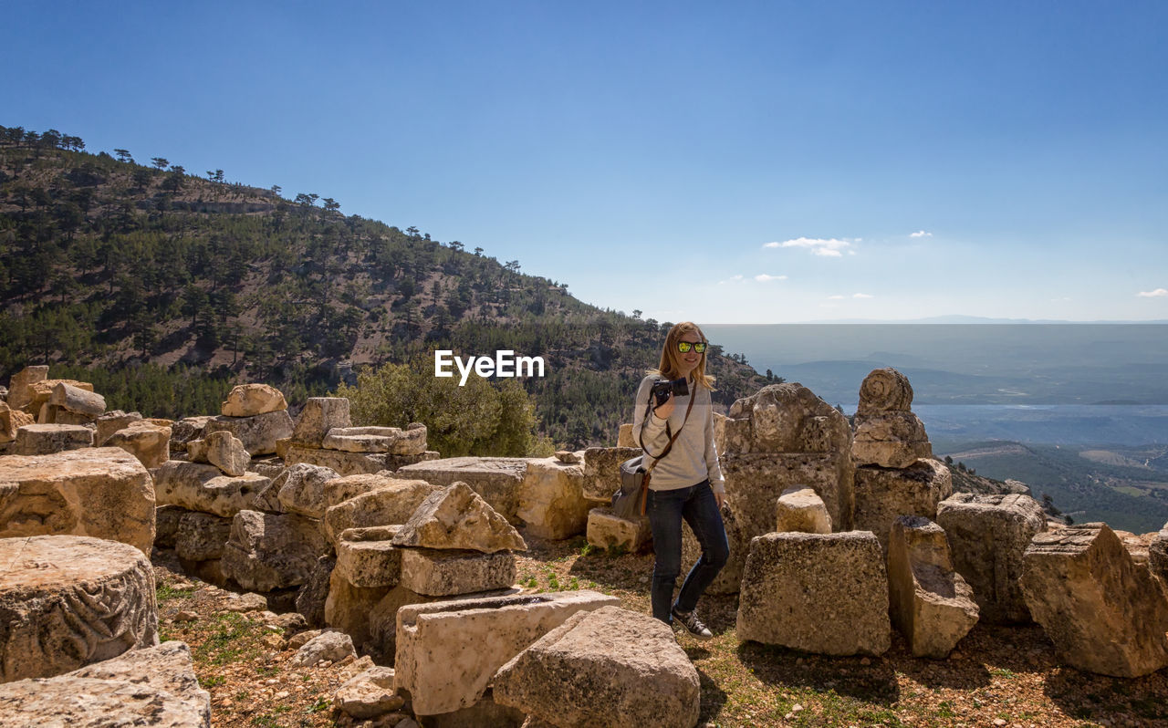 Woman standing by old ruins against sky