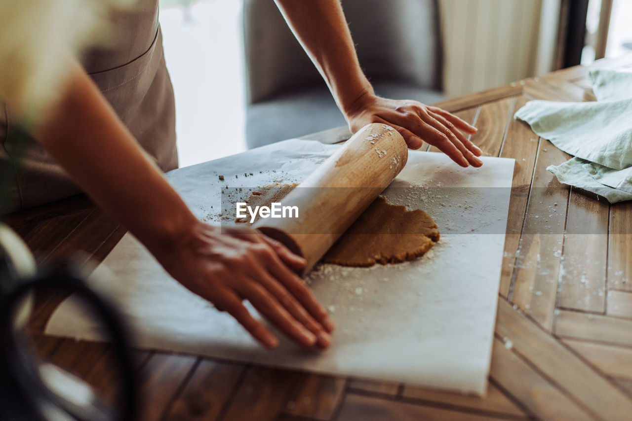 Process of rolling dough for cookies at table, crop on hand