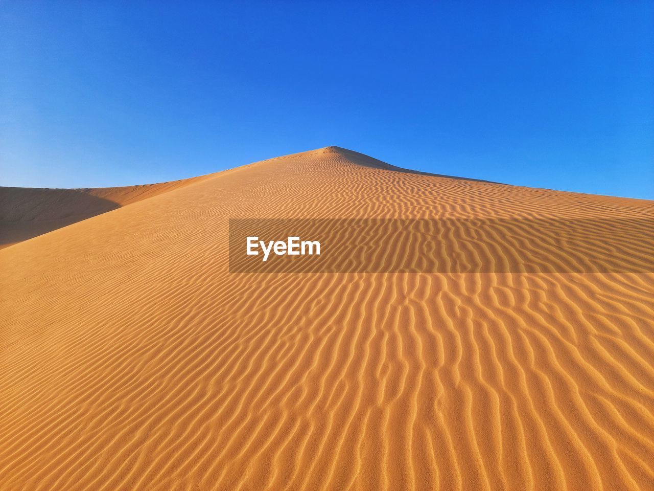 Sand dune in desert against clear blue sky