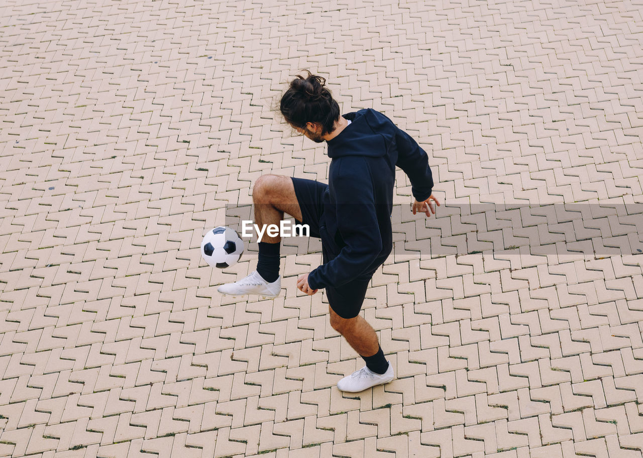 Sportsman kicking soccer ball with knee