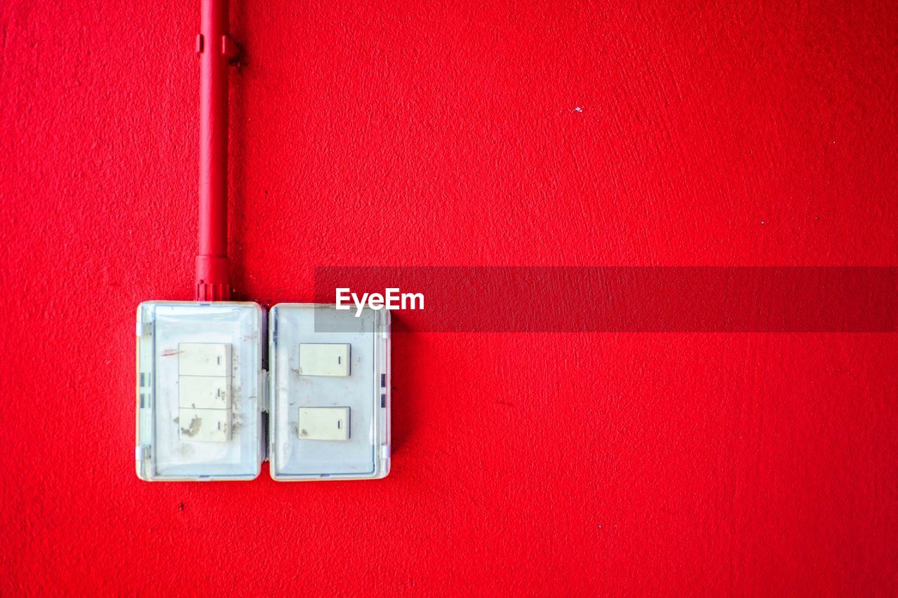 Close-up of light switch on red wall