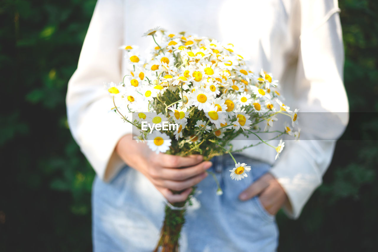 Midsection of woman holding white flower