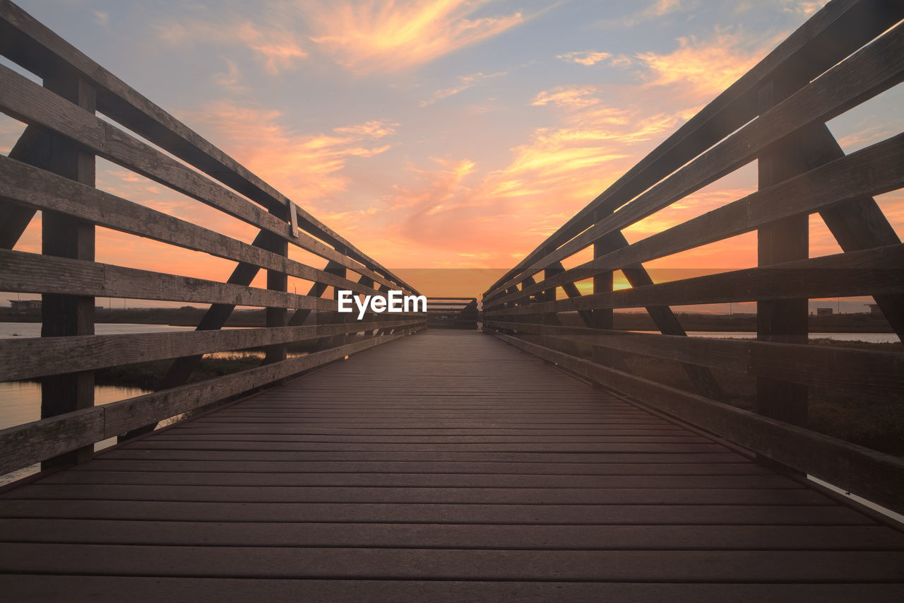 Wooden bridge against cloudy sky