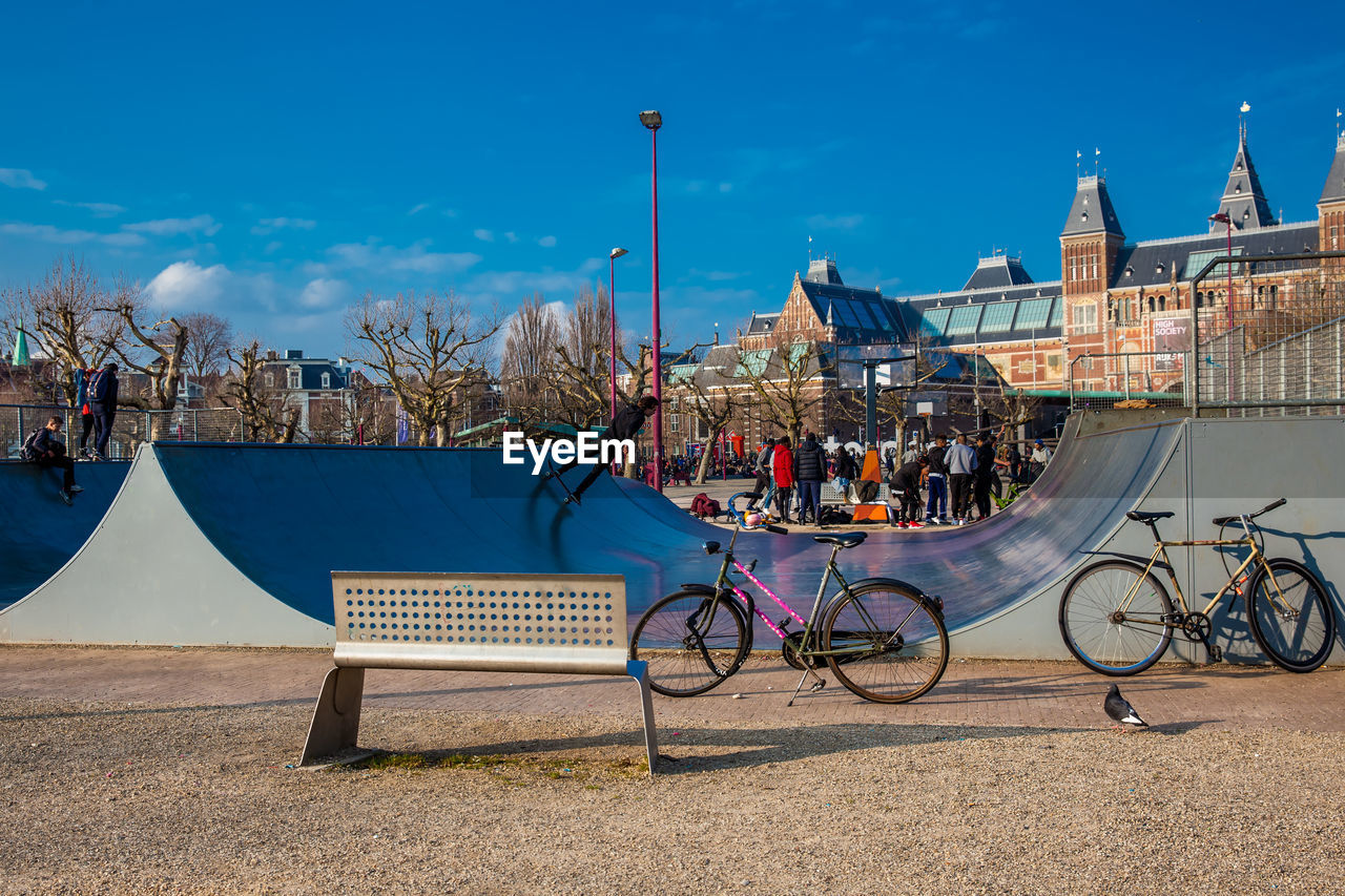 BICYCLES ON BENCH AGAINST BUILDINGS IN CITY