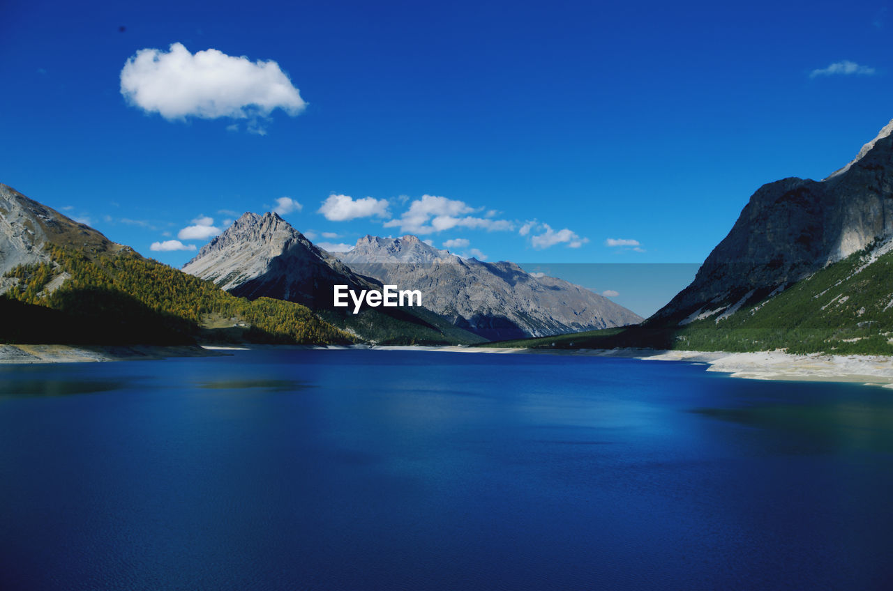 Scenic view of lake and mountains against blue sky