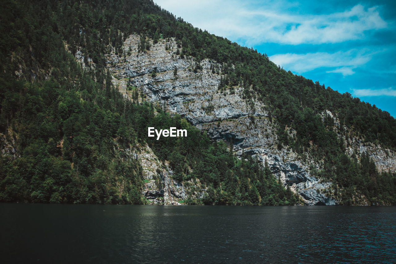 Scenic view of river by mountains against sky