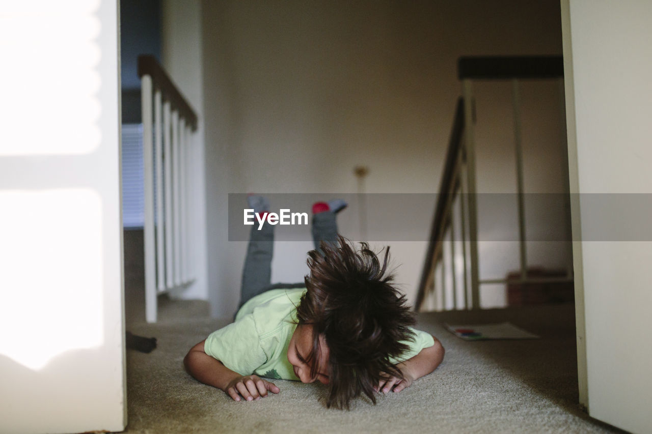 Boy laughing while lying on rug at home