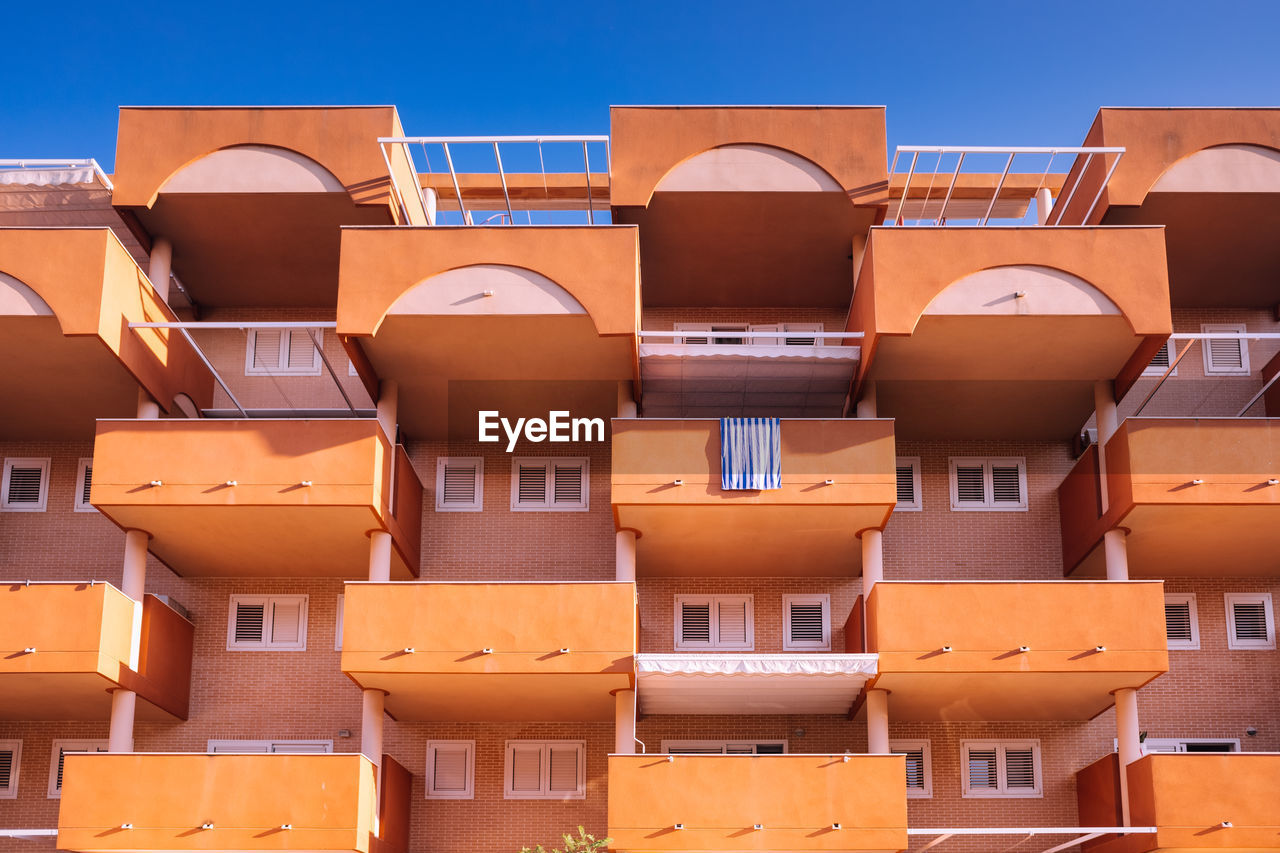 Facade of a block of holiday apartments on the beach, all with an outdoor balcony.