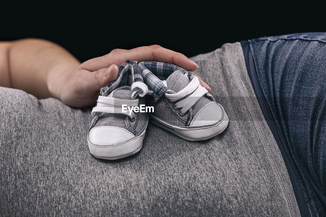 Midsection of pregnant woman holding small shoes