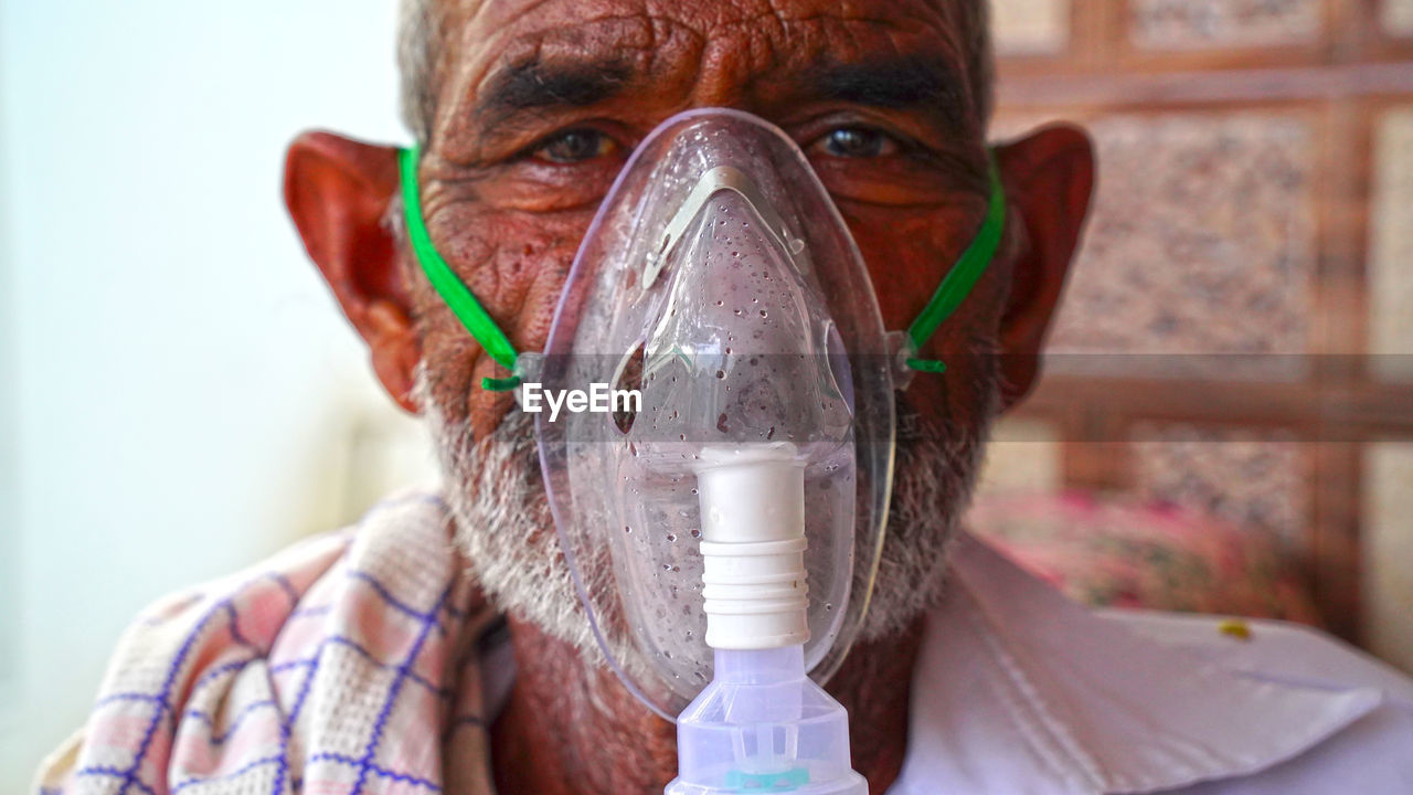 Close-up portrait of senior wearing oxygen mask