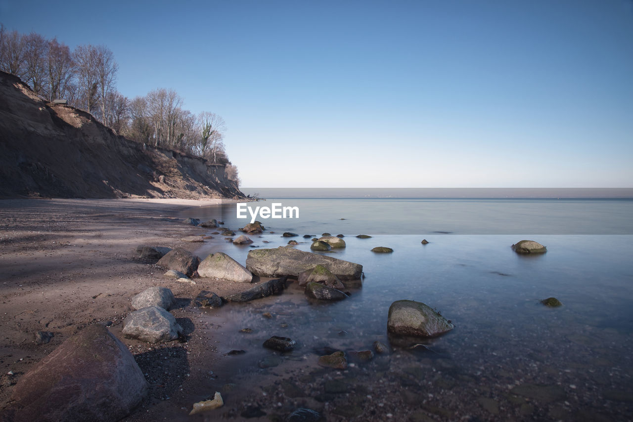 Rocks in sea against clear sky