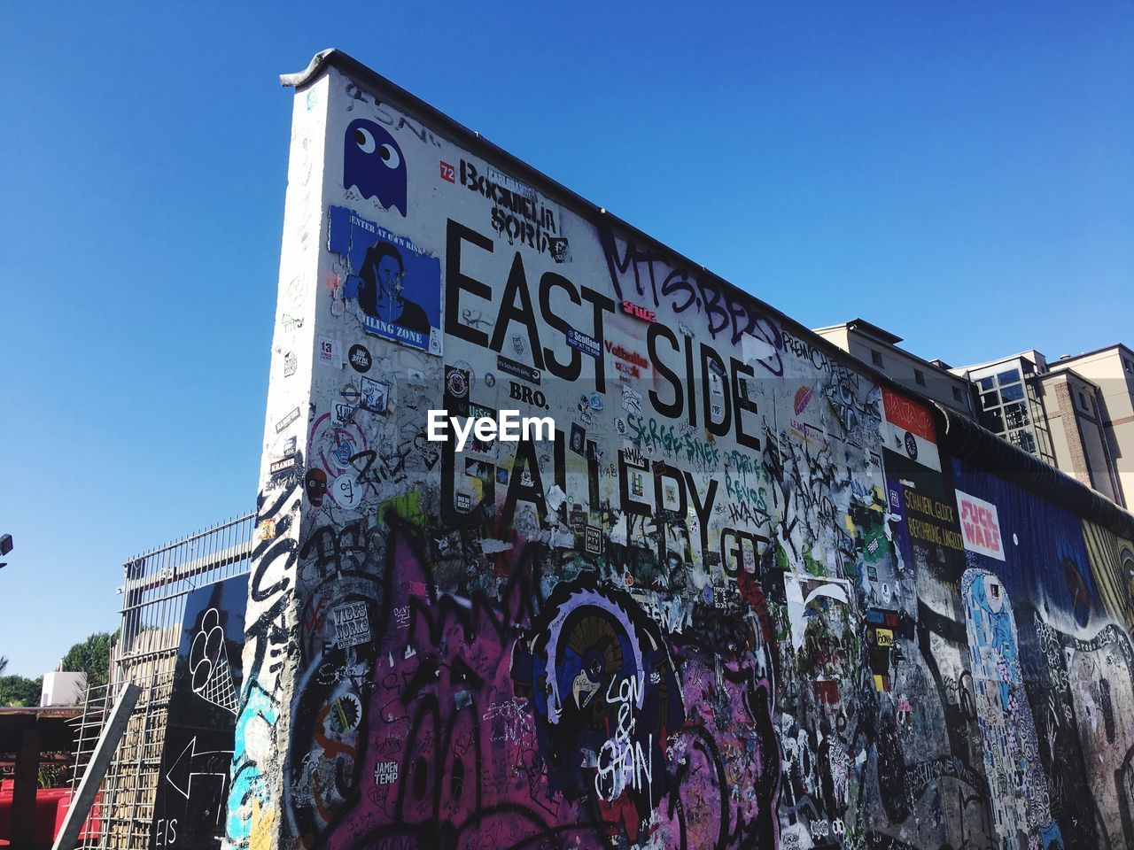 Low angle view of graffiti on building against blue sky - east side gallery berlin 