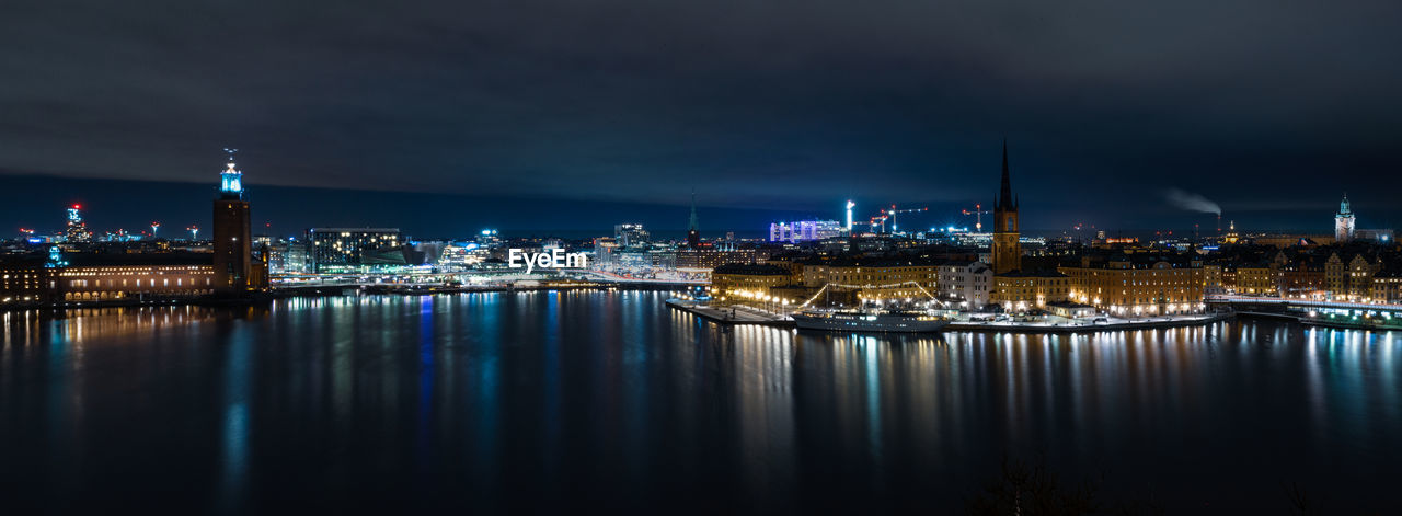 Illuminated buildings in stockholm city at night with reflections in waterfront