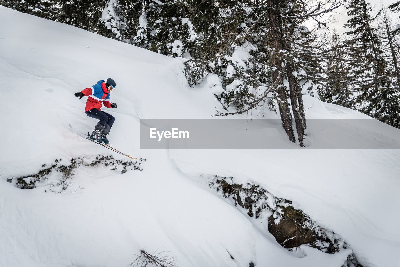 MAN SKIING ON SNOW COVERED MOUNTAINS