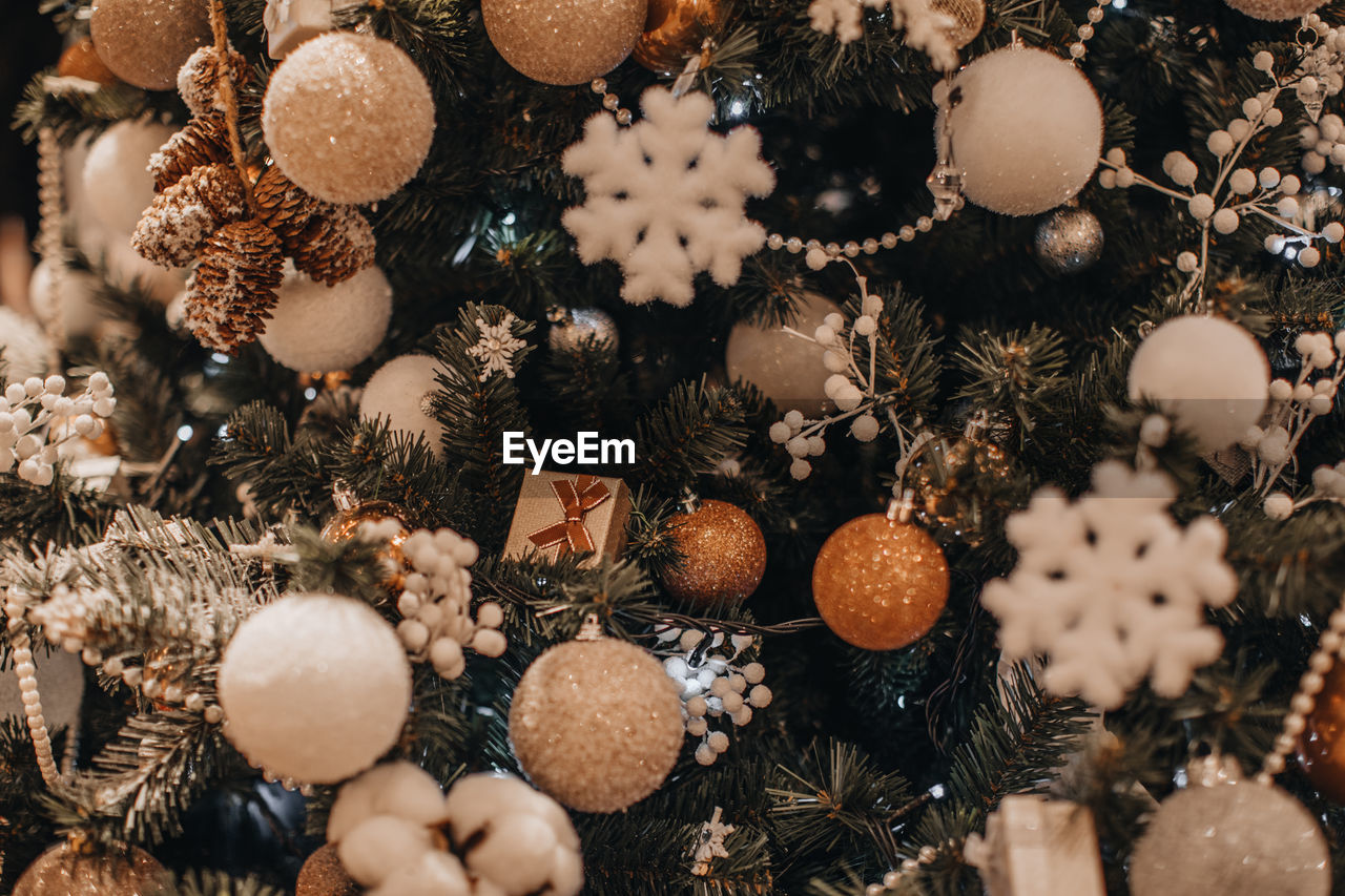 Christmas tree decorated with gold and white festive christmas balls, gofts and snowflakes. 