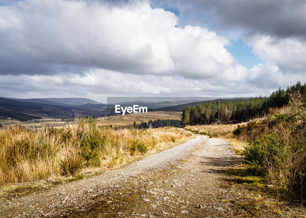 Dirt road along landscape against sky