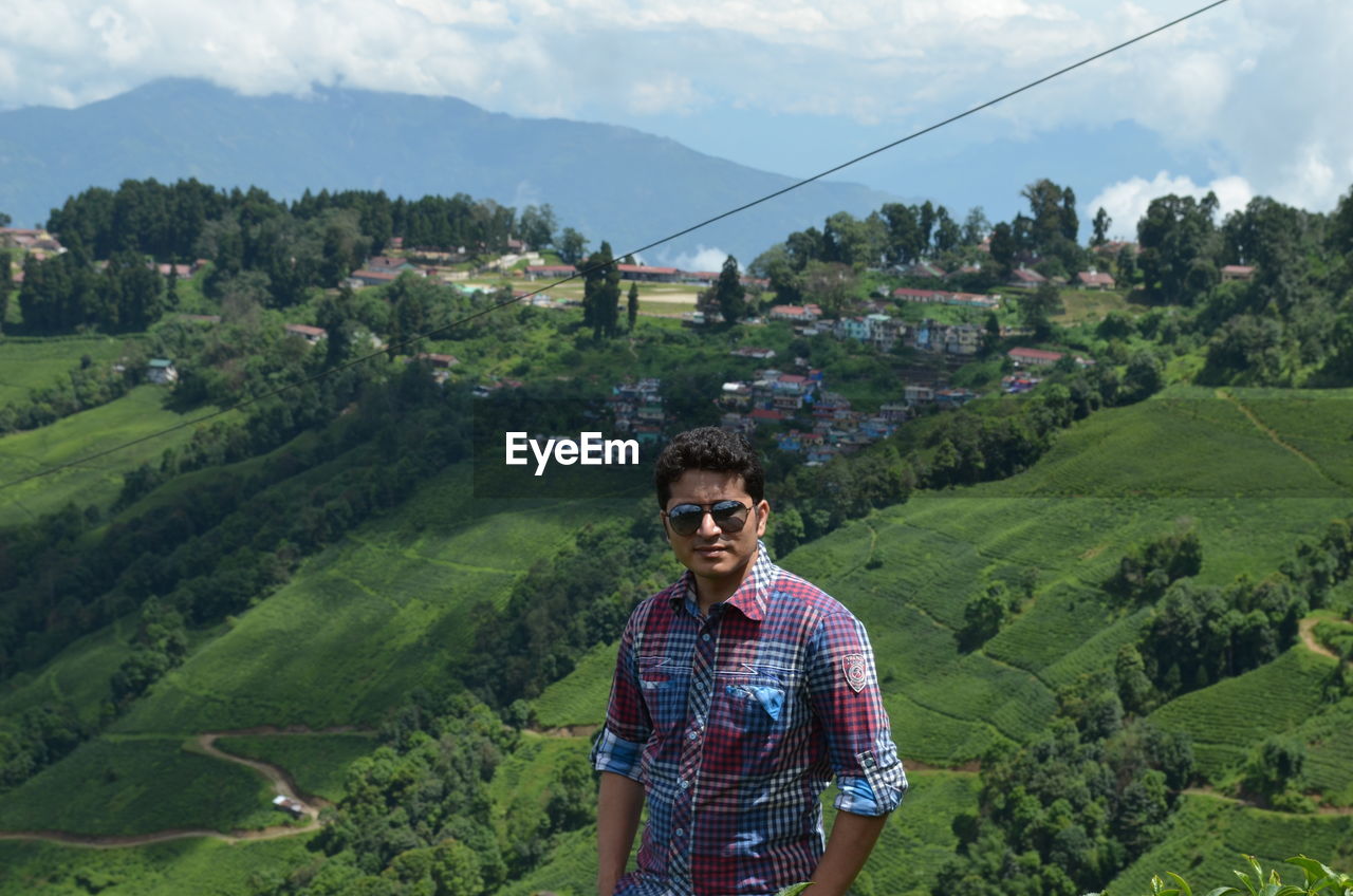 Portrait of young man wearing sunglasses standing on mountain