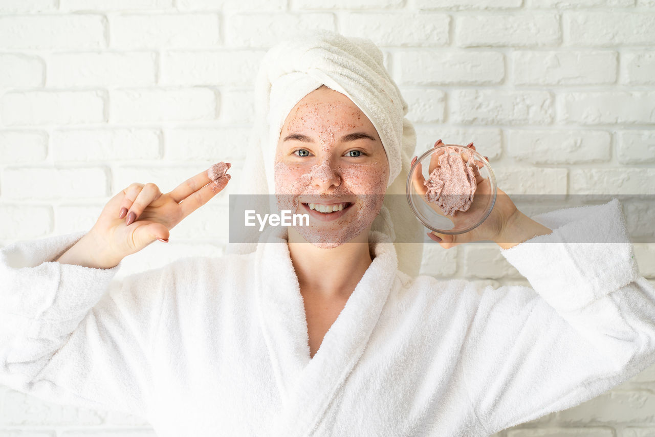 Portrait of a smiling young woman with face scrub