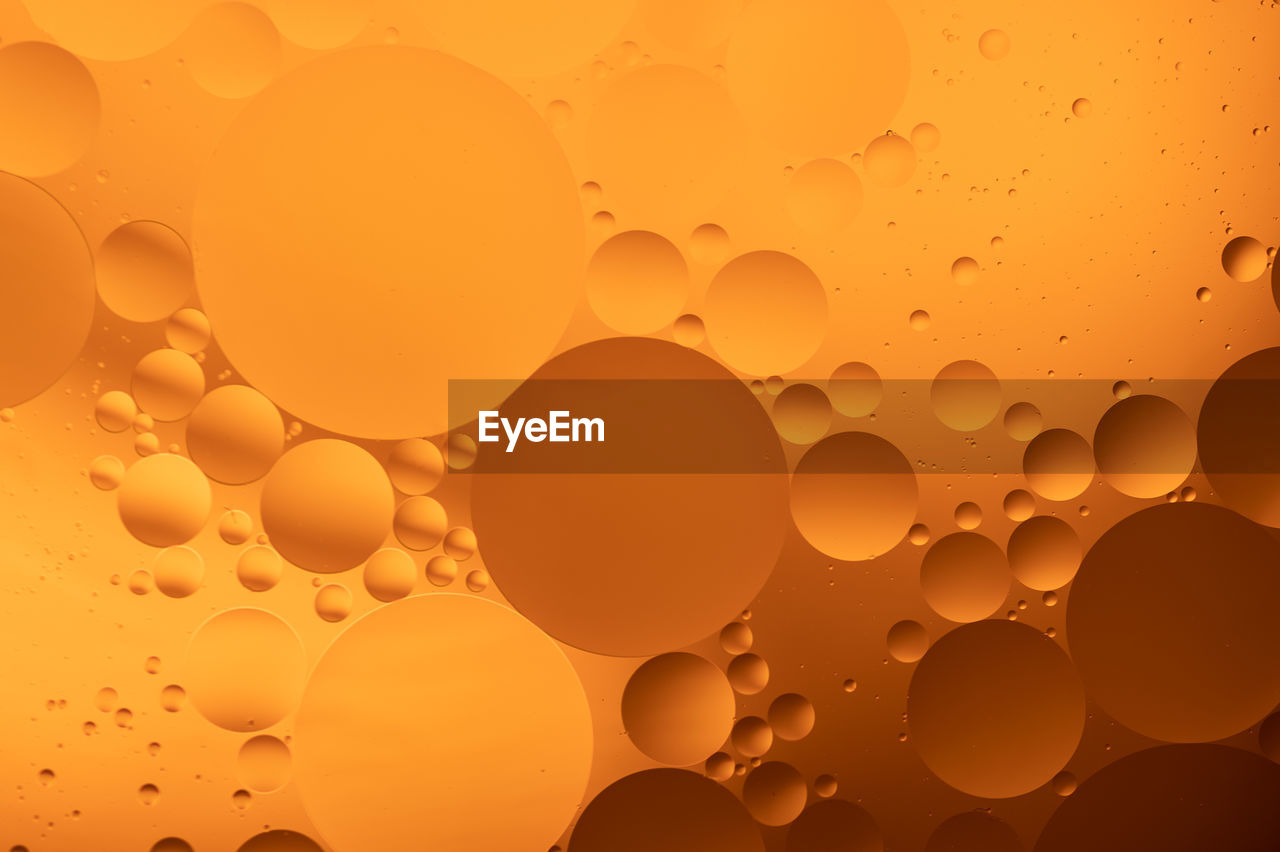 FULL FRAME SHOT OF BUBBLES IN WATER WITH ORANGE