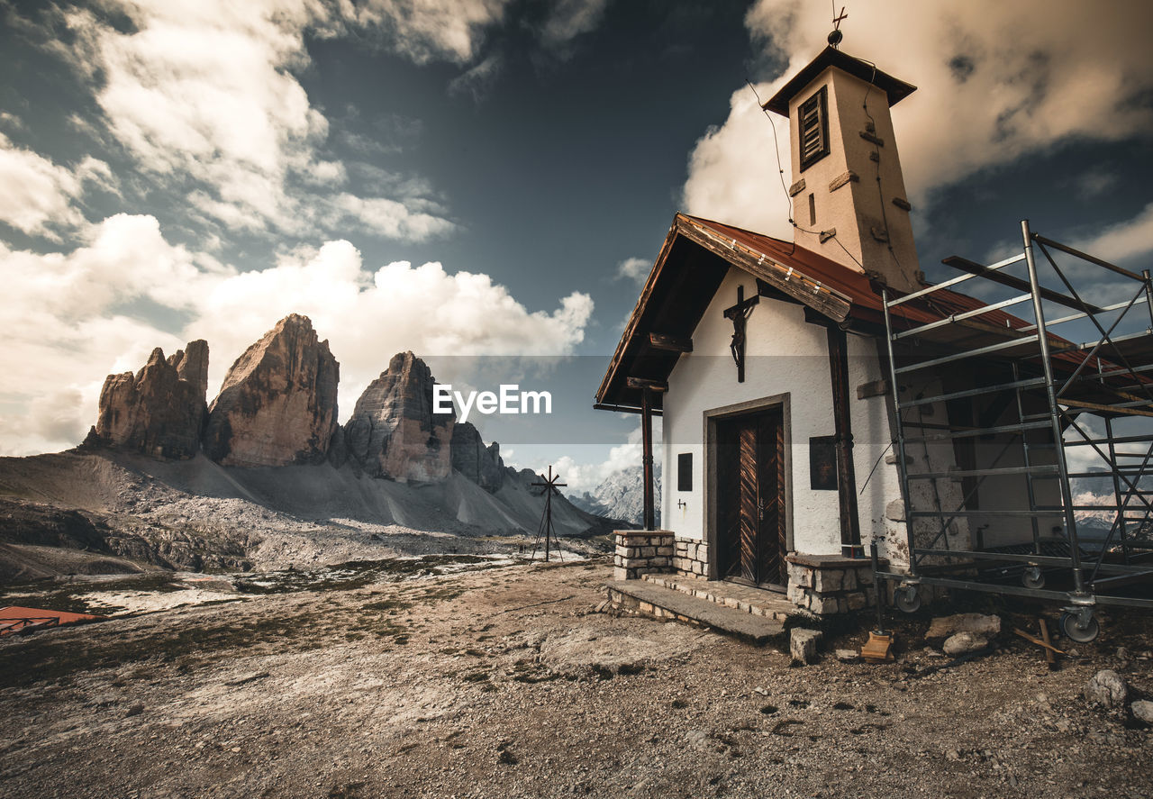 Old building by mountain against sky