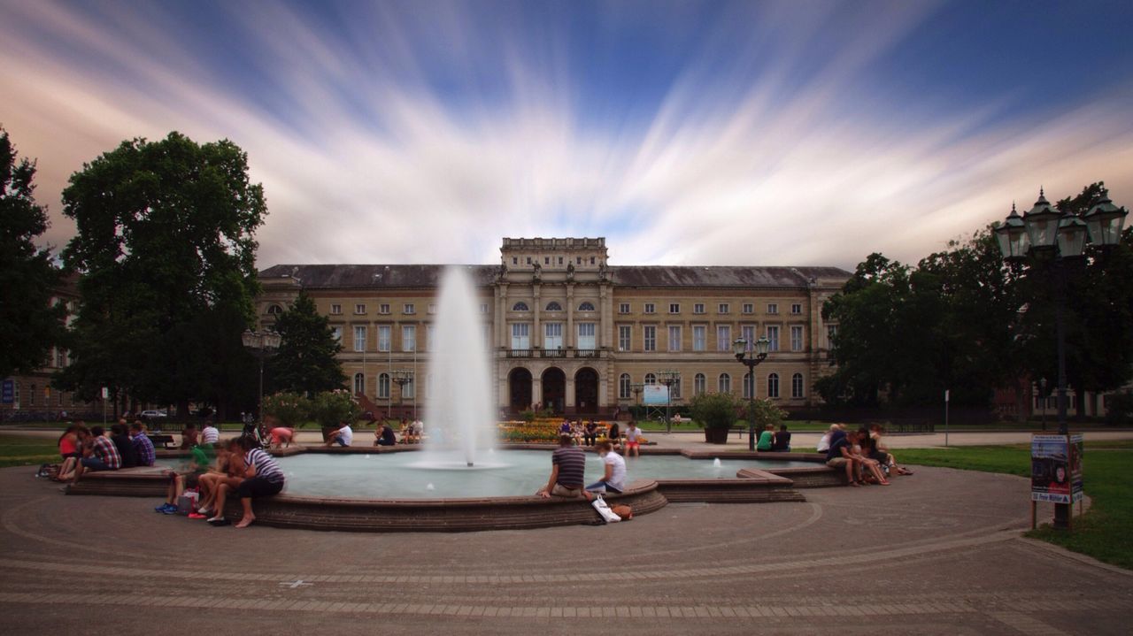 People sitting at fountain against building