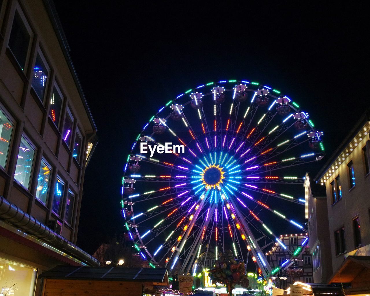 Low angle view of illuminated ferris wheel in town at night