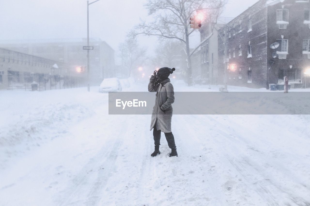 Side view of woman standing on snowcapped street during winter