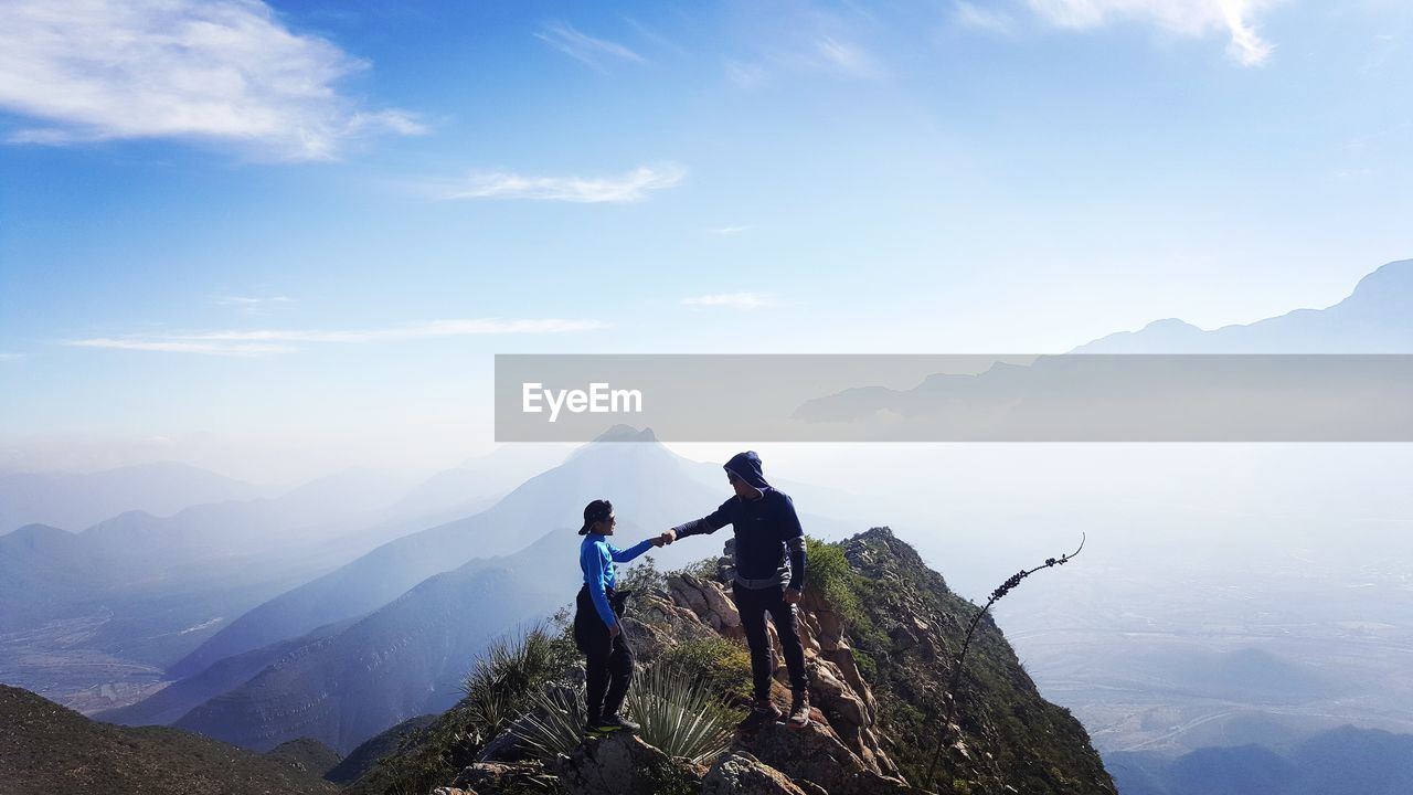 Couple standing on mountain against sky