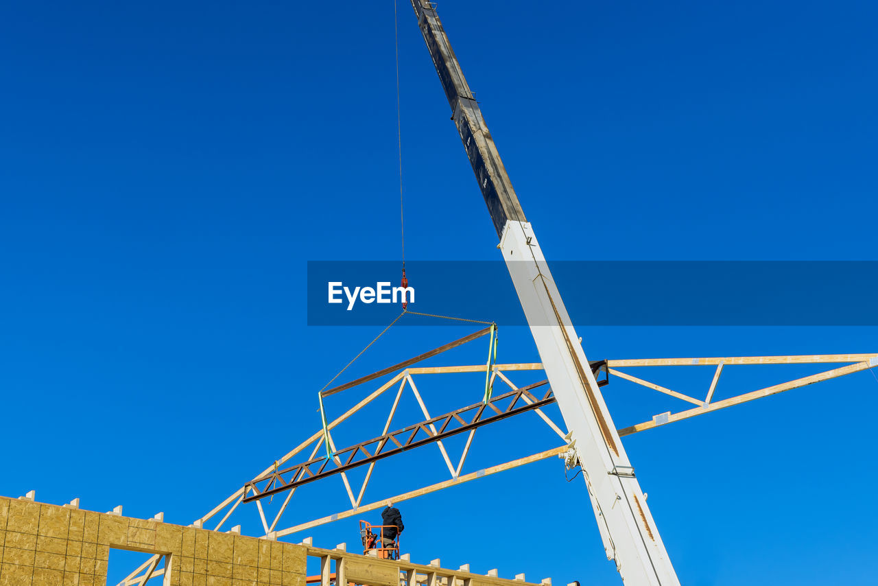 Low angle view of crane against blue sky