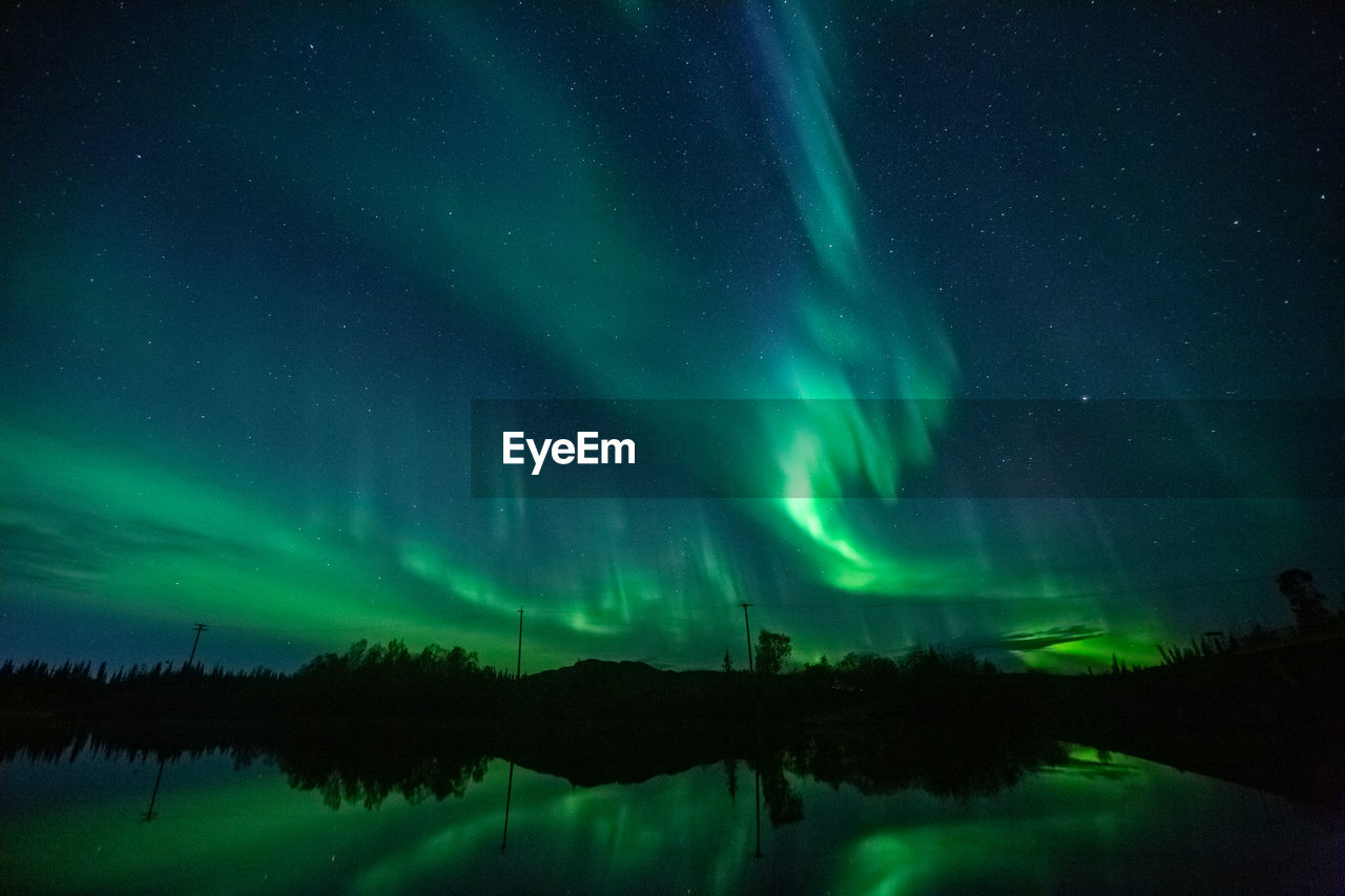 Aurora borealis is dancing above a lake at night