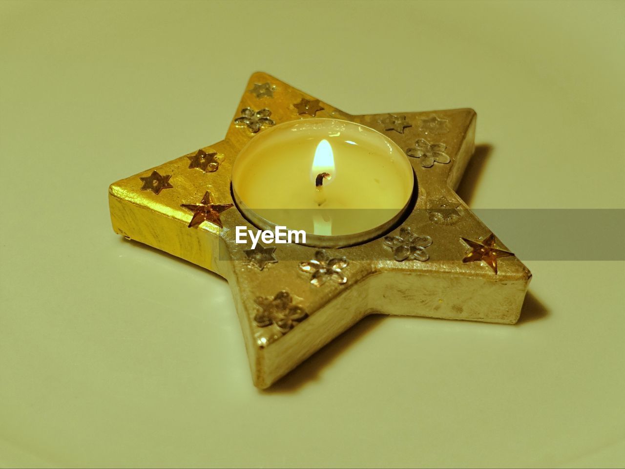 Close-up of star shape tea light candle on yellow background