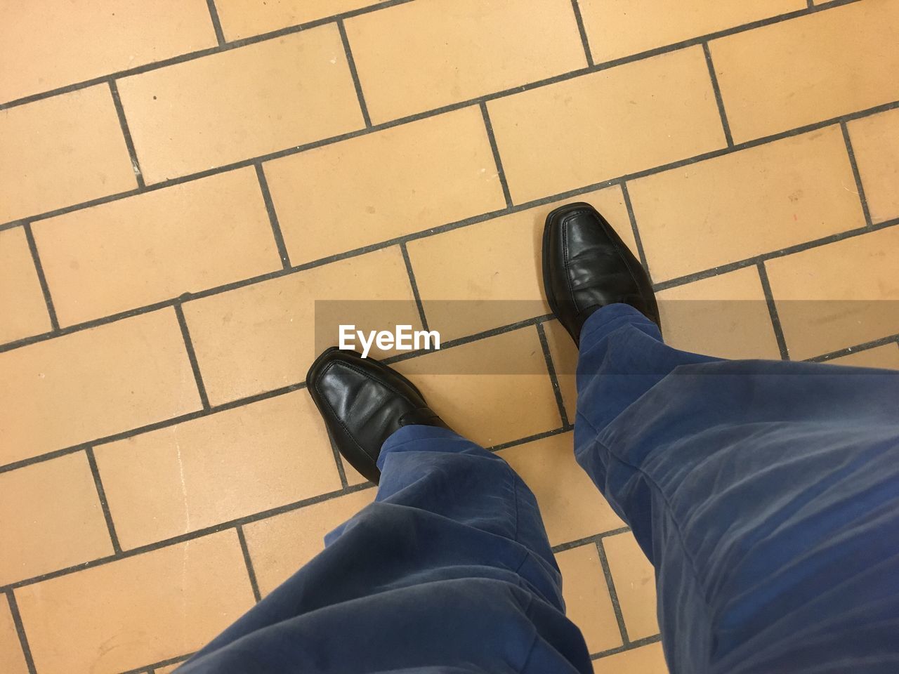 LOW SECTION OF MAN STANDING ON PAVING STONE