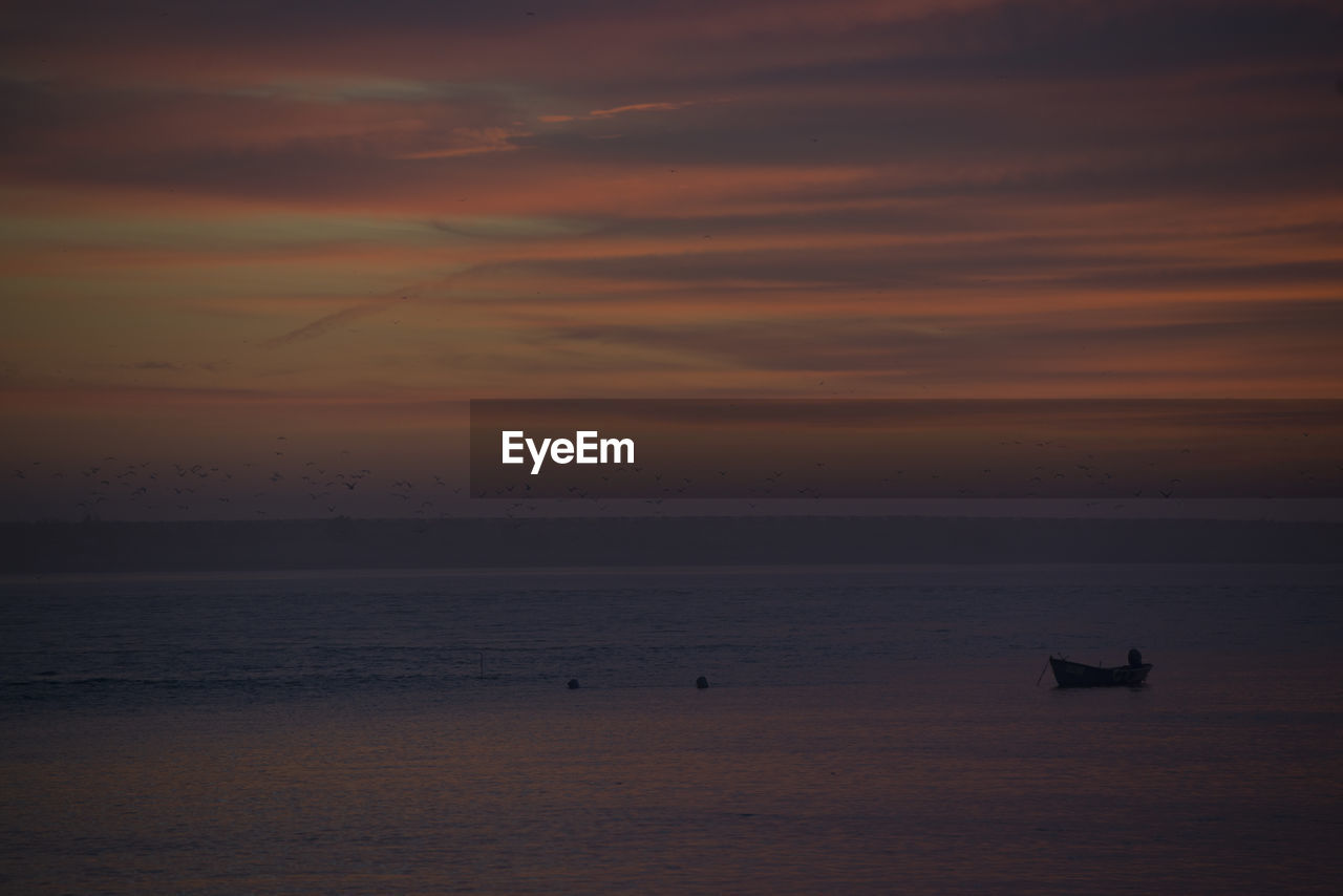 Silhouette boat in sea against sky during sunset