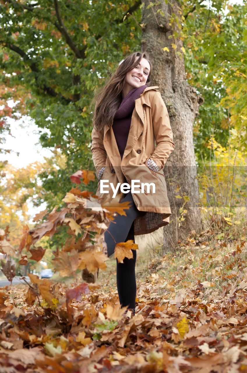 Low angle view of woman kicking fallen autumn leaves at park