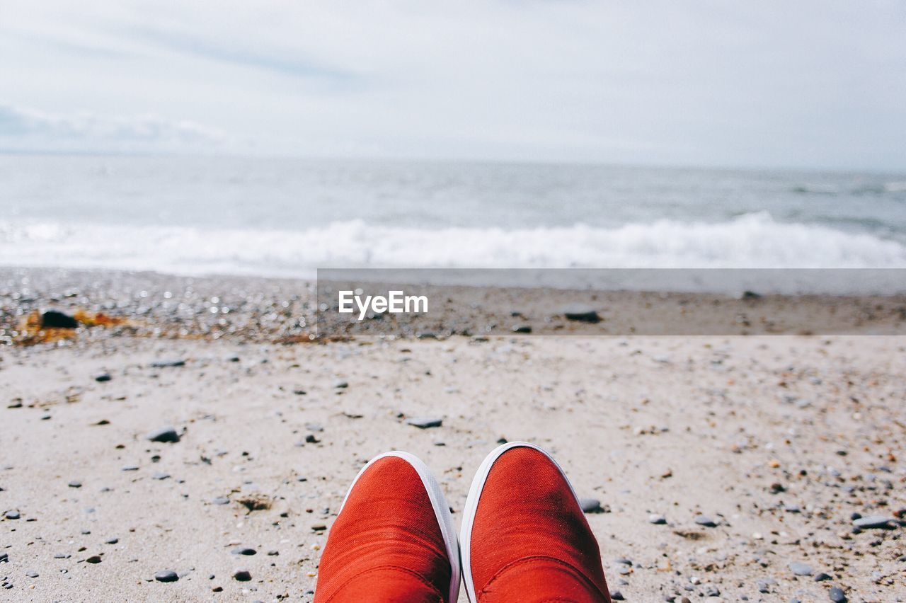 Close-up of shoes on beach against sea