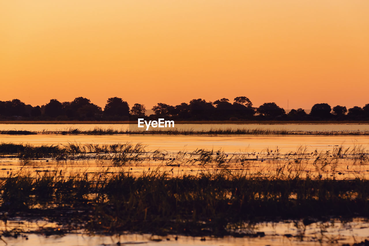 SCENIC VIEW OF LAKE AGAINST ORANGE SKY