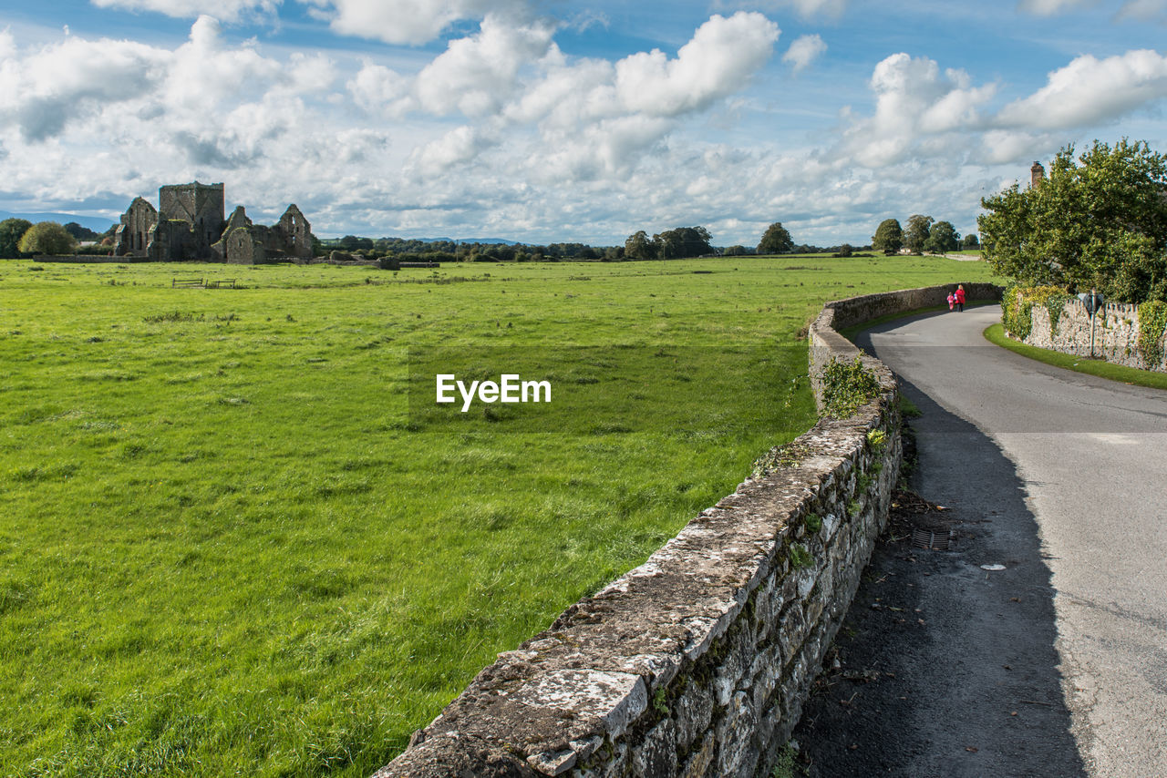 Road amidst field against sky