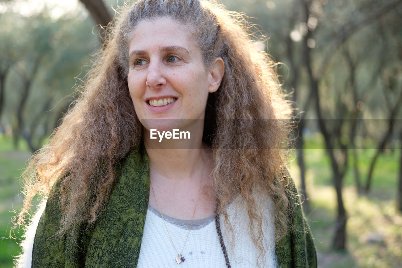 Smiling mature woman looking away in forest