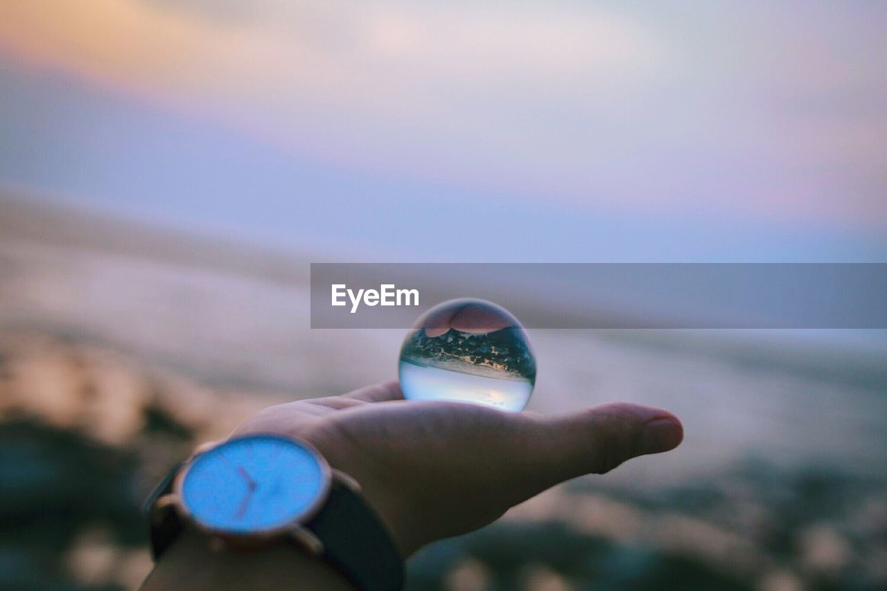 Close-up of hand holding crystal ball at beach